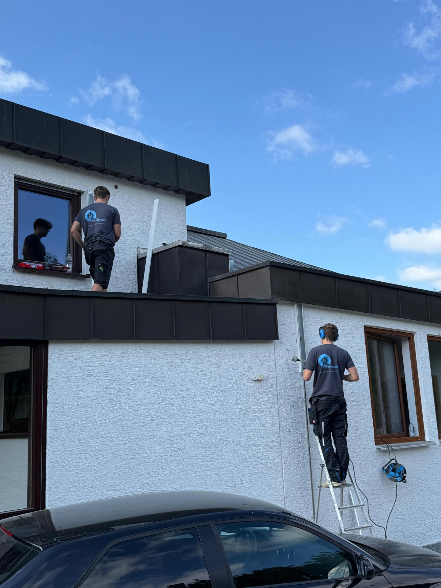 Zwei Handwerker bei der Installlation einer Split-Klimaanlage an einem Einfamilienhaus